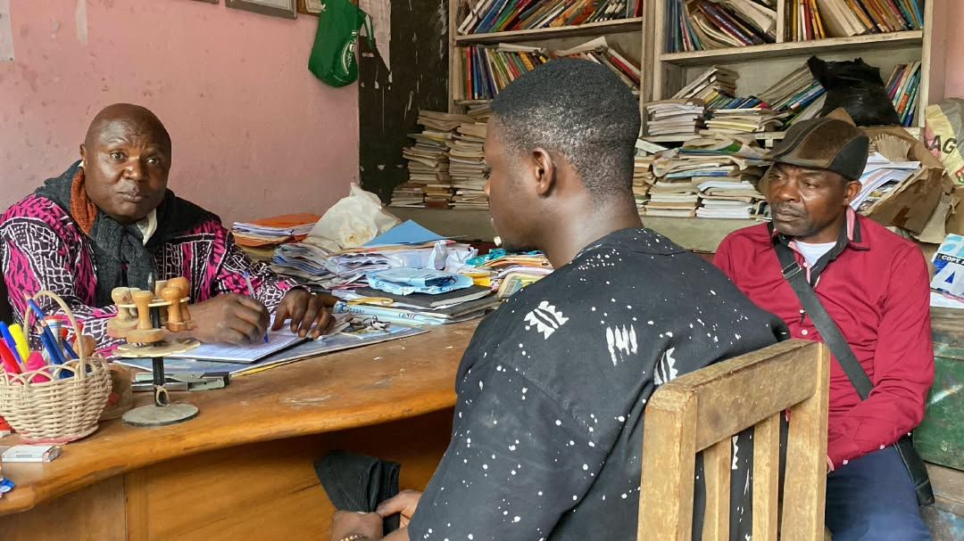 Un aîné conseille un jeune dans une bibliothèque
